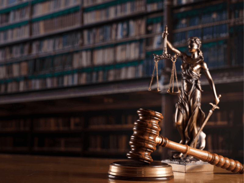 Biblioteca com a estátua da liberdade segurando uma balança na frente da estua temos um martelo